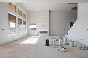 Unfurnished living room with a fireplace and a high ceiling