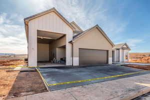View of front of property featuring a garage, board and batten siding, driveway, and stucco siding