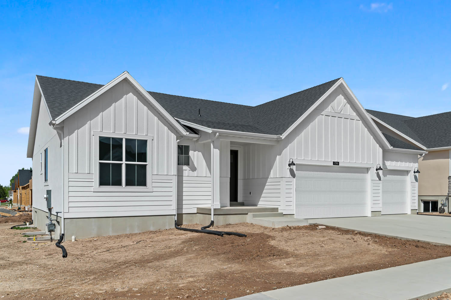 Modern inspired farmhouse featuring roof with shingles, board and batten siding, an attached garage, and driveway