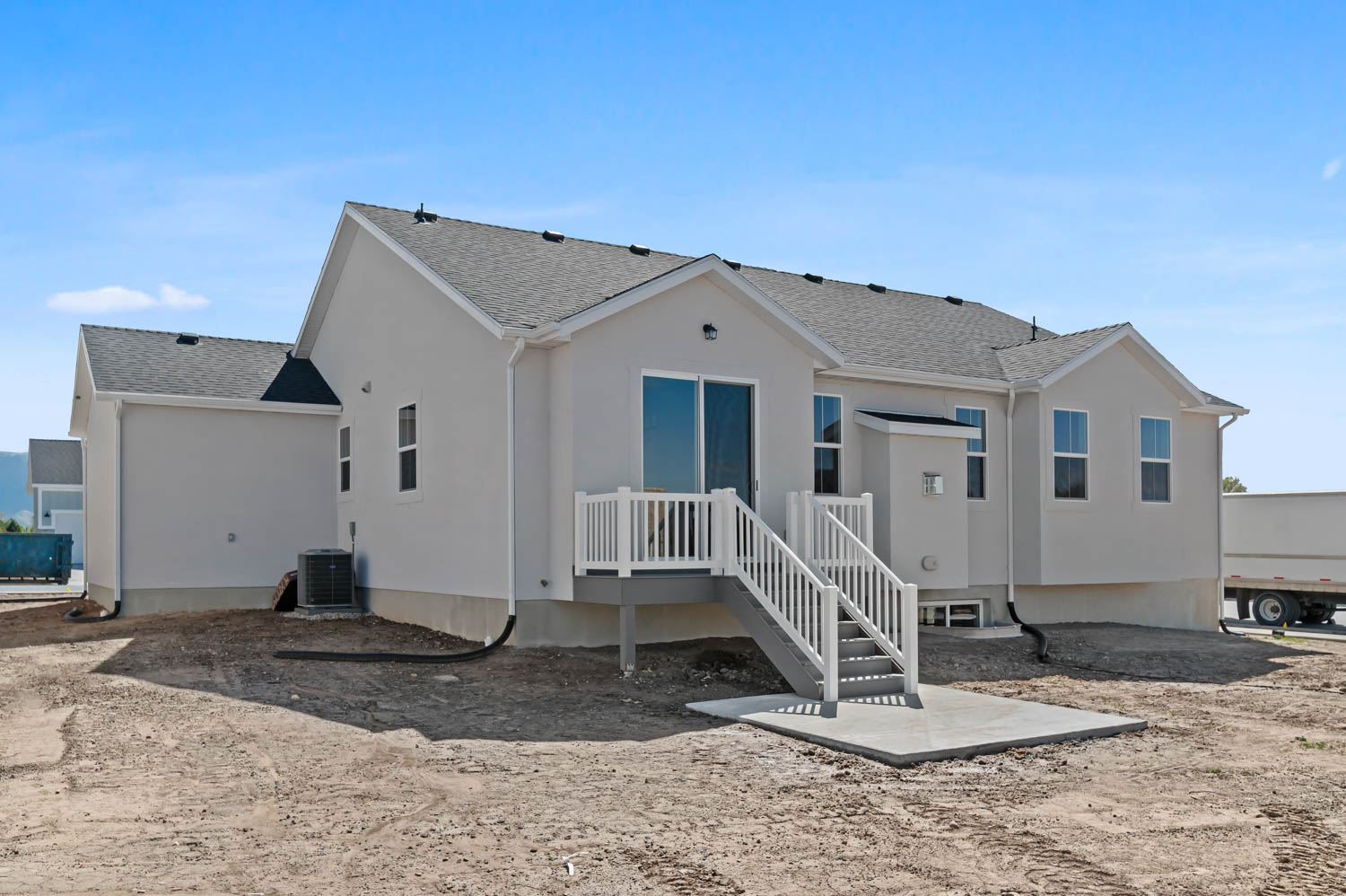 Back of house featuring a shingled roof, a wooden deck, and stucco siding