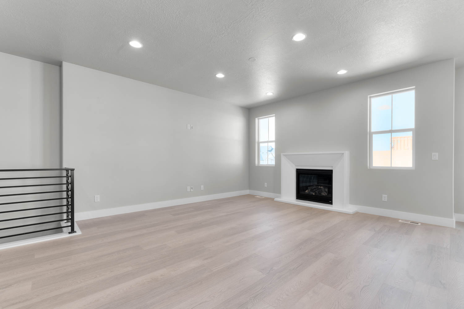 Unfurnished living room featuring recessed lighting, a glass covered fireplace, light wood finished floors, and a textured ceiling