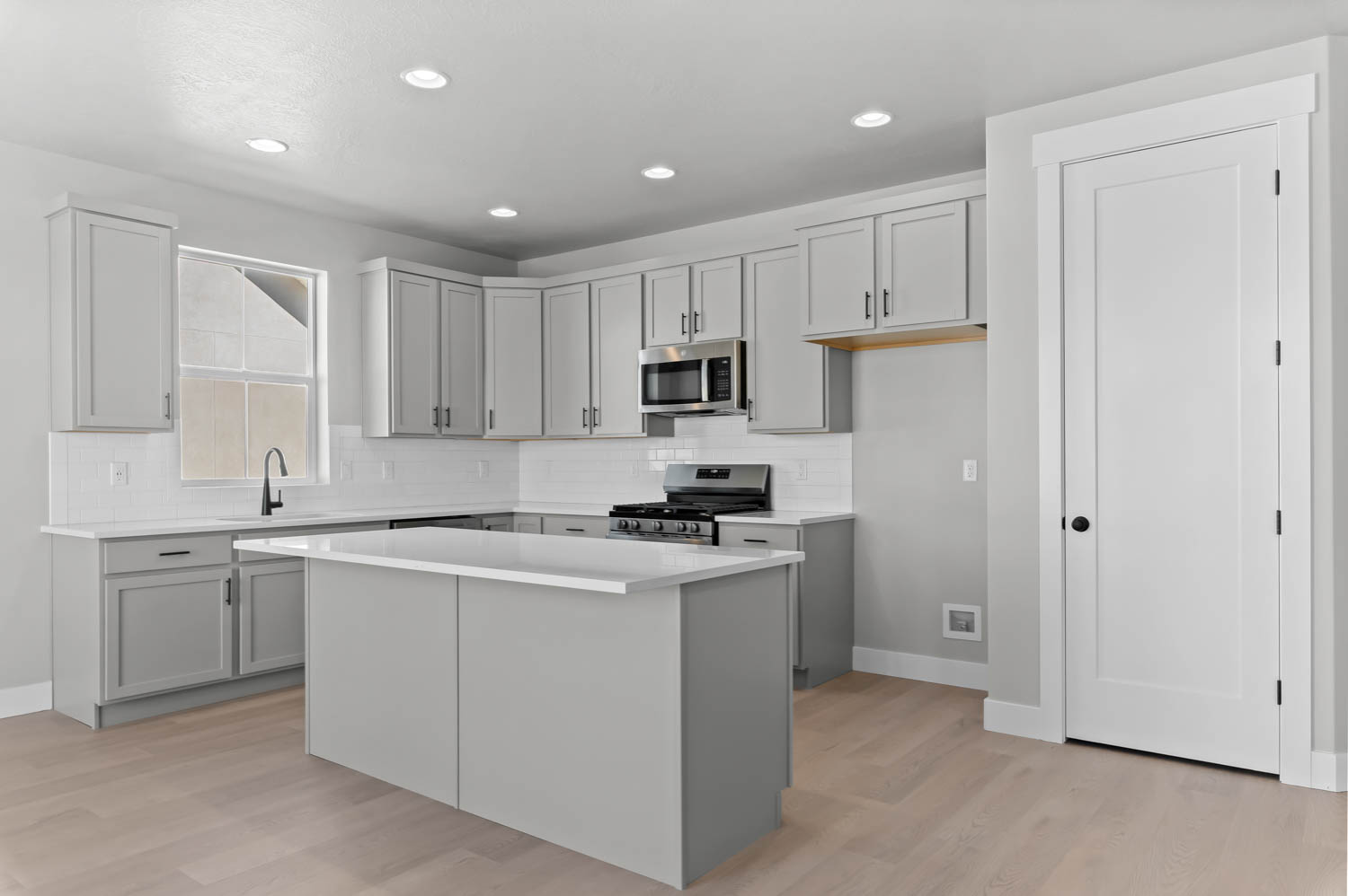 Kitchen featuring stainless steel appliances, tasteful backsplash, light wood finished floors, a kitchen island, and gray cabinets