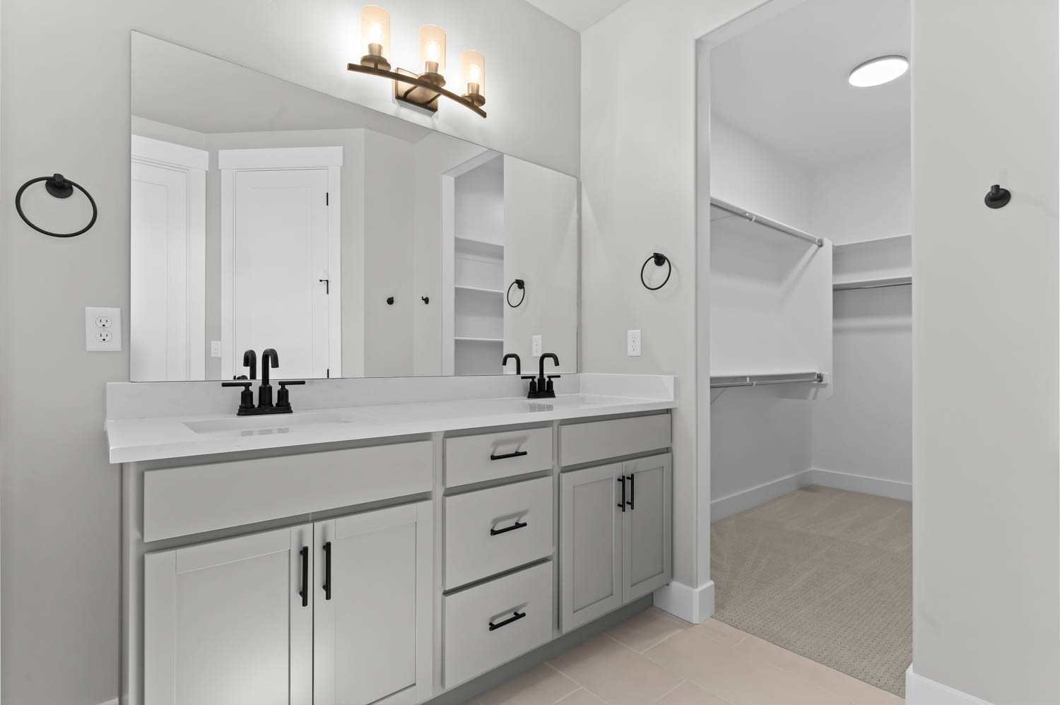 Full bathroom with double vanity, light carpet, a spacious closet, and light tile patterned flooring