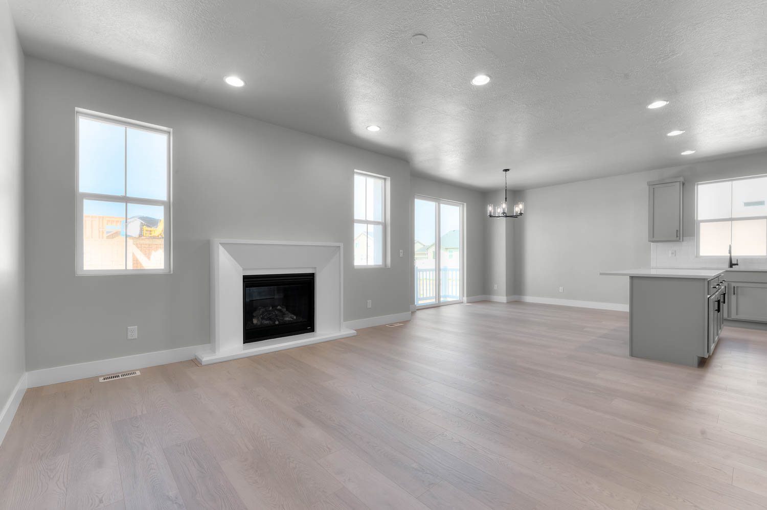 Unfurnished living room with light wood-style floors, a glass covered fireplace, a chandelier, and a textured ceiling