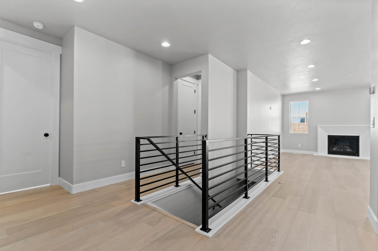 Corridor featuring an upstairs landing, light wood-style flooring, and recessed lighting