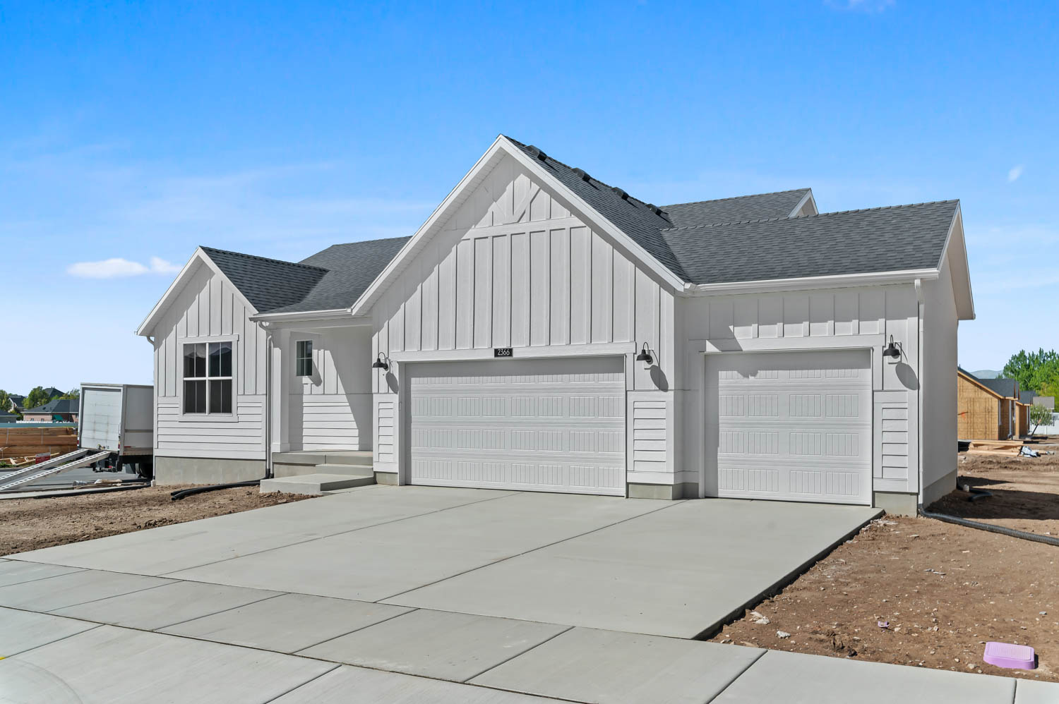 View of front of property featuring board and batten siding, a garage, a shingled roof, and driveway
