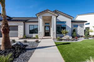 View of front of home featuring stone siding, a garage, a front lawn, and driveway