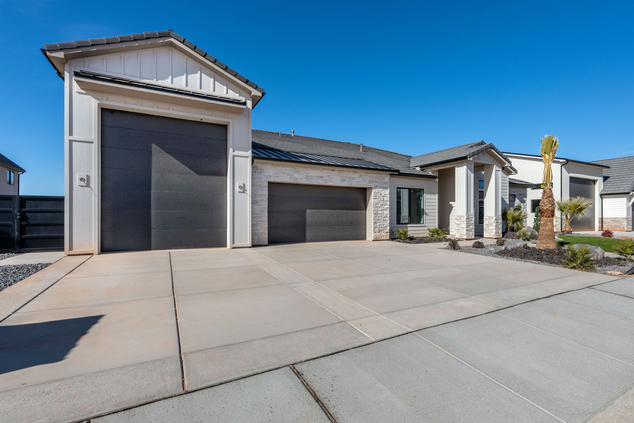 View of front of property featuring stone siding, an attached garage, driveway, and a standing seam roof