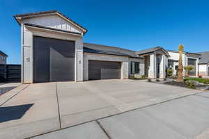 View of front of property featuring stone siding, an attached garage, driveway, and a standing seam roof