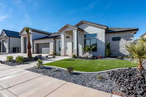 View of front facade with stone siding, a front lawn, an attached garage, concrete driveway, and a tile roof