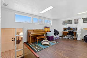 Living area featuring a desk, wood finished floors, healthy amount of natural light, and a textured ceiling
