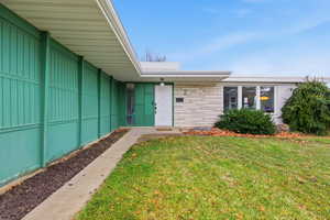 Entrance to property featuring a lawn and stone siding