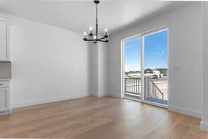 Unfurnished dining area featuring suspended lighting and light wood-type flooring