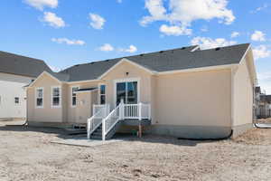 Back of house featuring stucco siding and roof with shingles