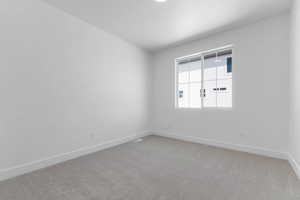 Spare room featuring light carpet and baseboards
