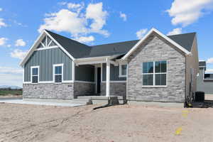 View of front of property with stone siding, board and batten siding, and covered porch