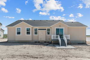 Back of property featuring roof with shingles and stucco siding