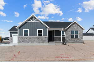View of front of home with stone siding, board and batten siding, a porch, and an attached garage