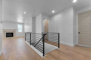 Hallway with an upstairs landing, recessed lighting, and light wood finished floors
