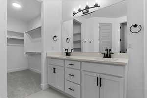 Full bath with a spacious closet, double vanity, and light carpet