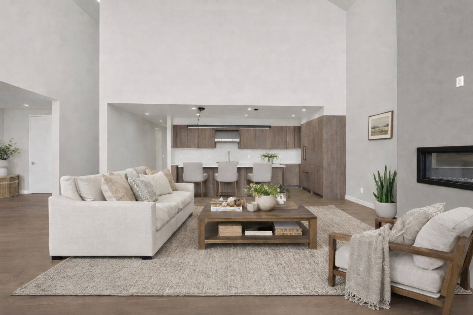 Living area with a high ceiling, light wood-style flooring, and a glass covered fireplace