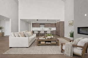 Living area with a high ceiling, light wood-style flooring, and a glass covered fireplace