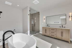 Full bathroom with a stall shower, double vanity, and a freestanding tub