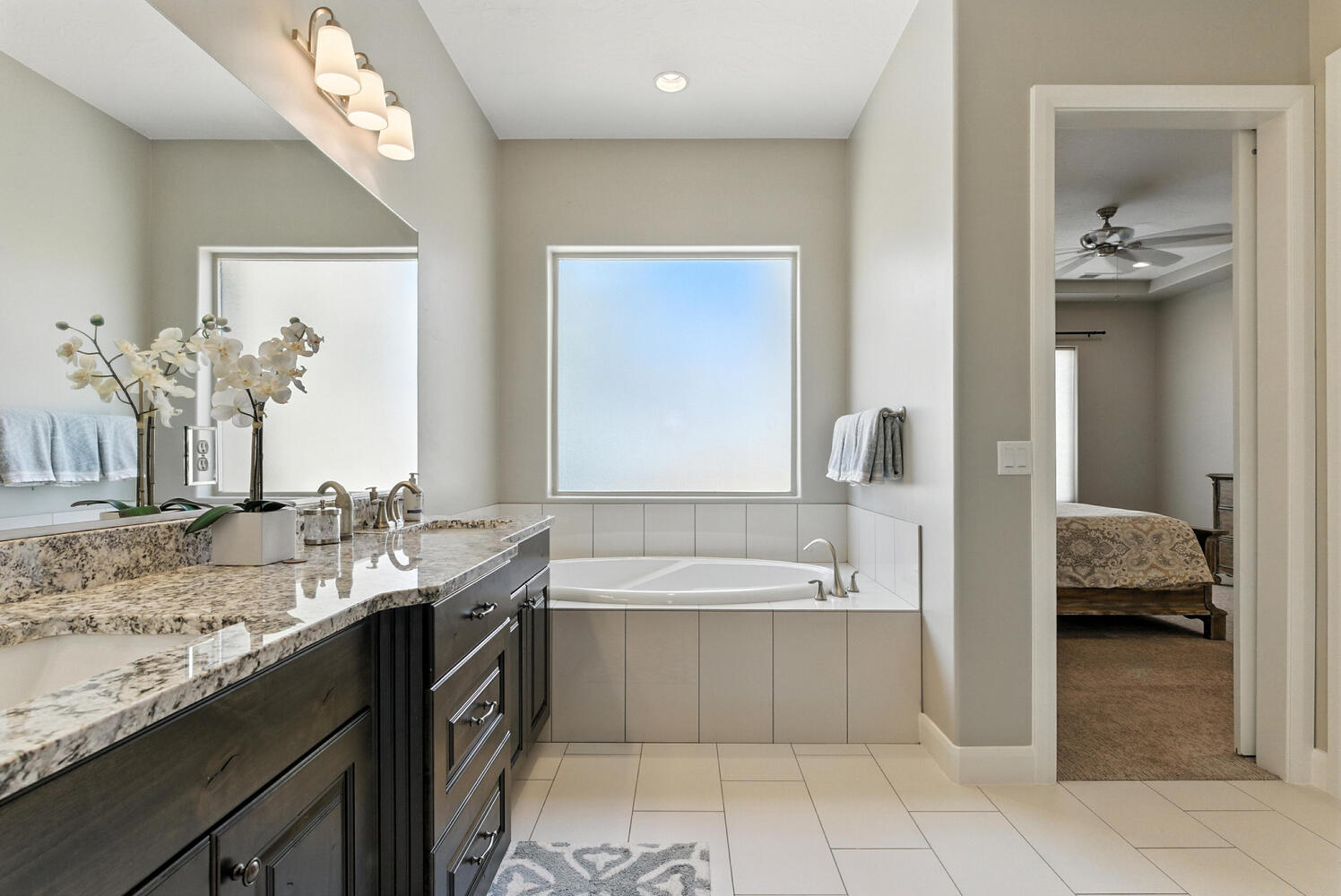 Bathroom with double vanity, ensuite bath, a bath, ceiling fan, and light tile patterned floors
