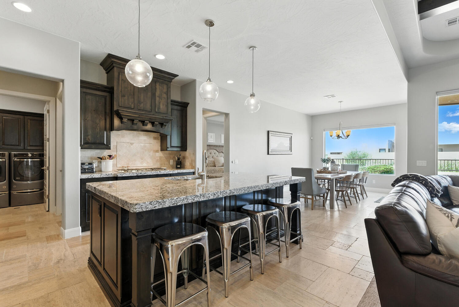 Kitchen featuring open floor plan, light stone counters, tasteful backsplash, a kitchen breakfast bar, and dark wood finish cabinets
