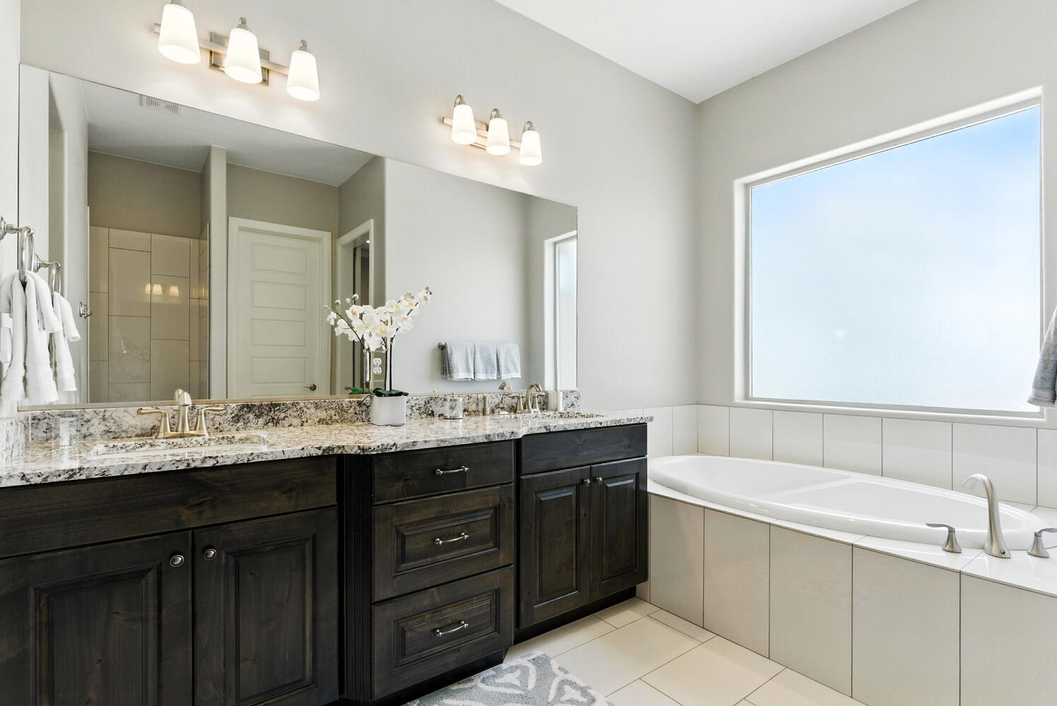 Bathroom featuring double vanity, a garden tub, and light tile patterned floors
