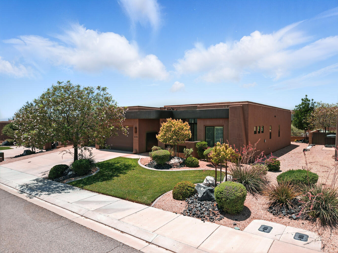 View of front of home featuring driveway, a front lawn, a garage, and stucco siding