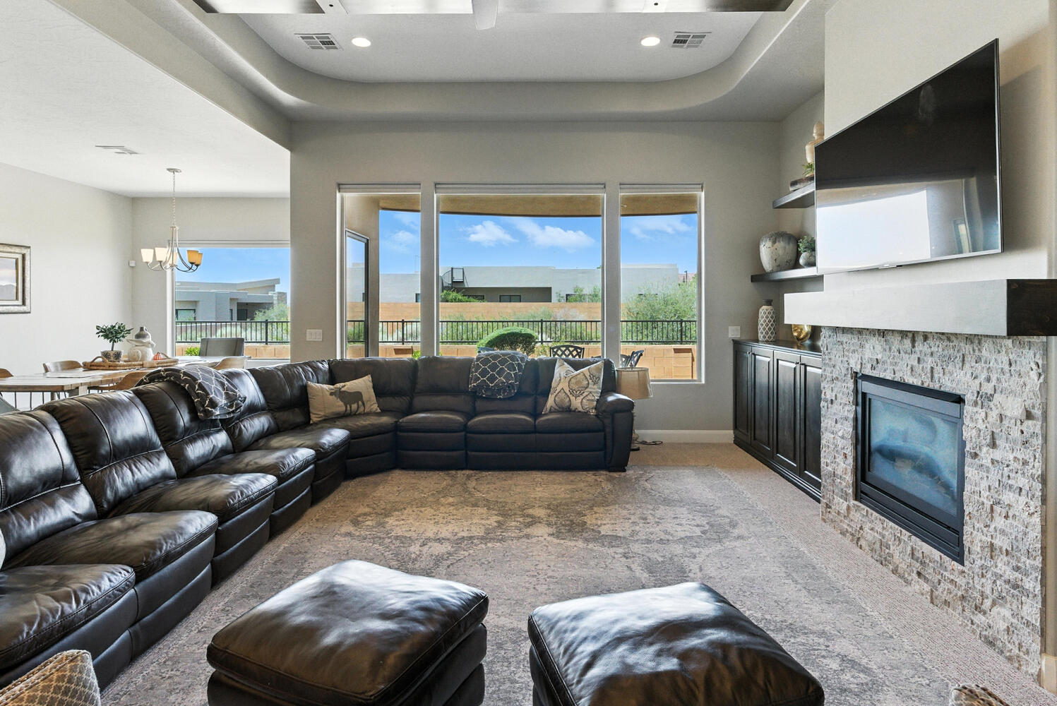 Living room featuring carpet, a glass covered fireplace, suspended lighting, plenty of natural light, and a raised ceiling