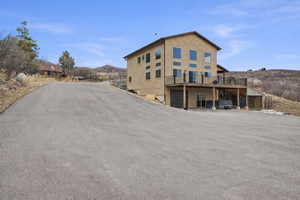Rear view of property featuring a garage, a deck with mountain view, asphalt driveway, and a patio area
