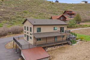 Back of property featuring a deck and a shingled roof