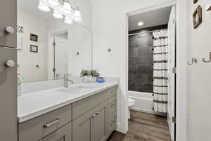 Bathroom with vanity, shower / bath combination with curtain, and dark wood finished floors