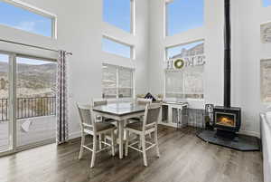 Dining room with a wood stove, wood finished floors, a high ceiling, and plenty of natural light