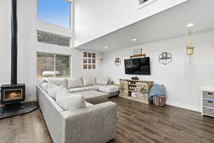 Living area featuring a high ceiling, dark wood finished floors, a wood stove, and recessed lighting