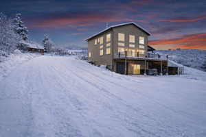 Snow covered back of property with a deck with mountain view