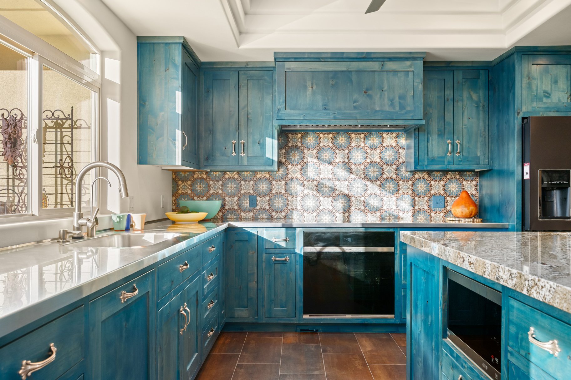Kitchen with blue cabinetry, stainless steel appliances, a tray ceiling, and tasteful backsplash