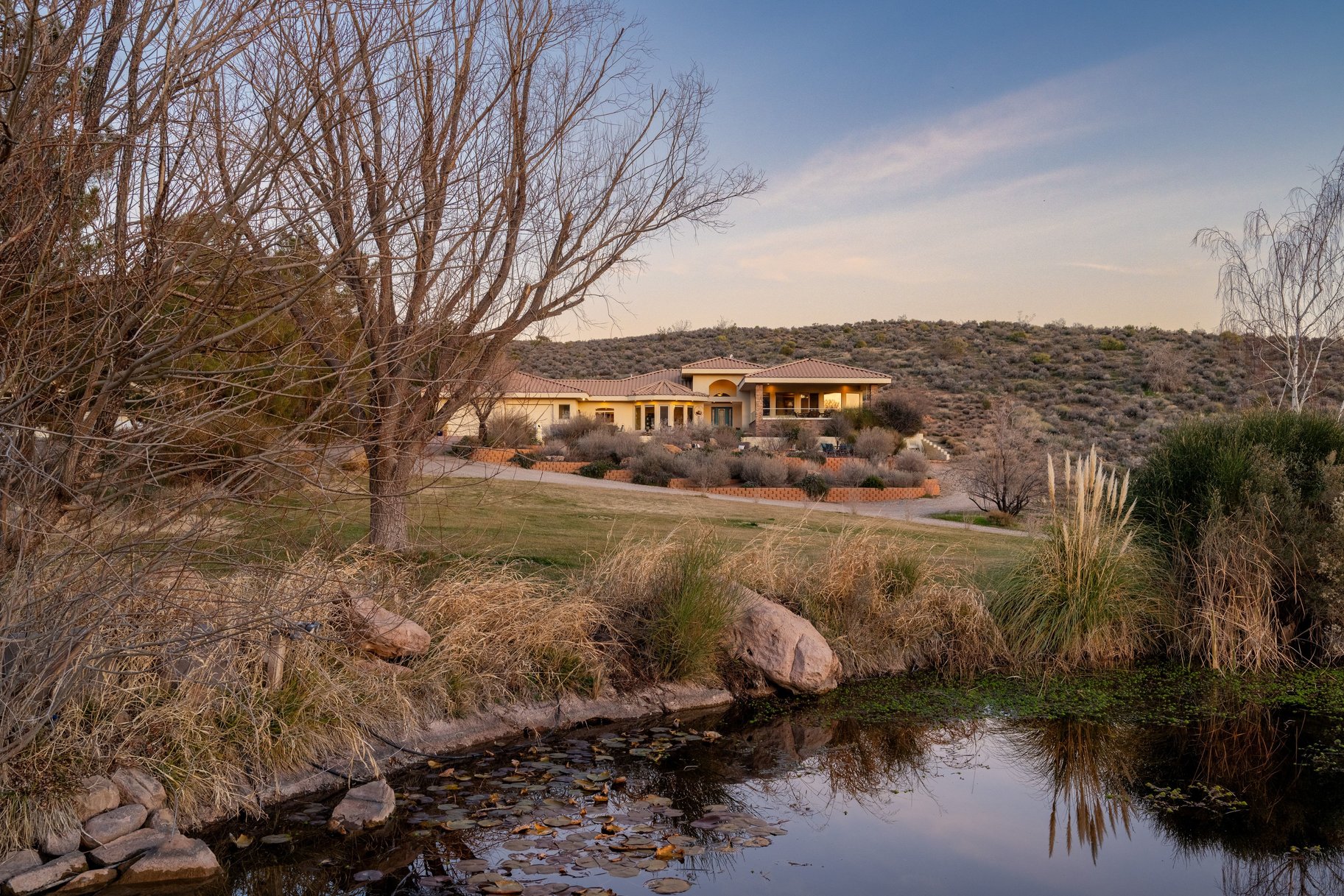 Back of property at dusk with a yard and a water view