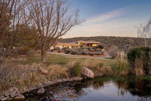 Back of property at dusk with a yard and a water view