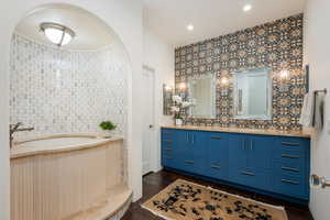 Bathroom with double vanity, dark wood-style floors, and recessed lighting