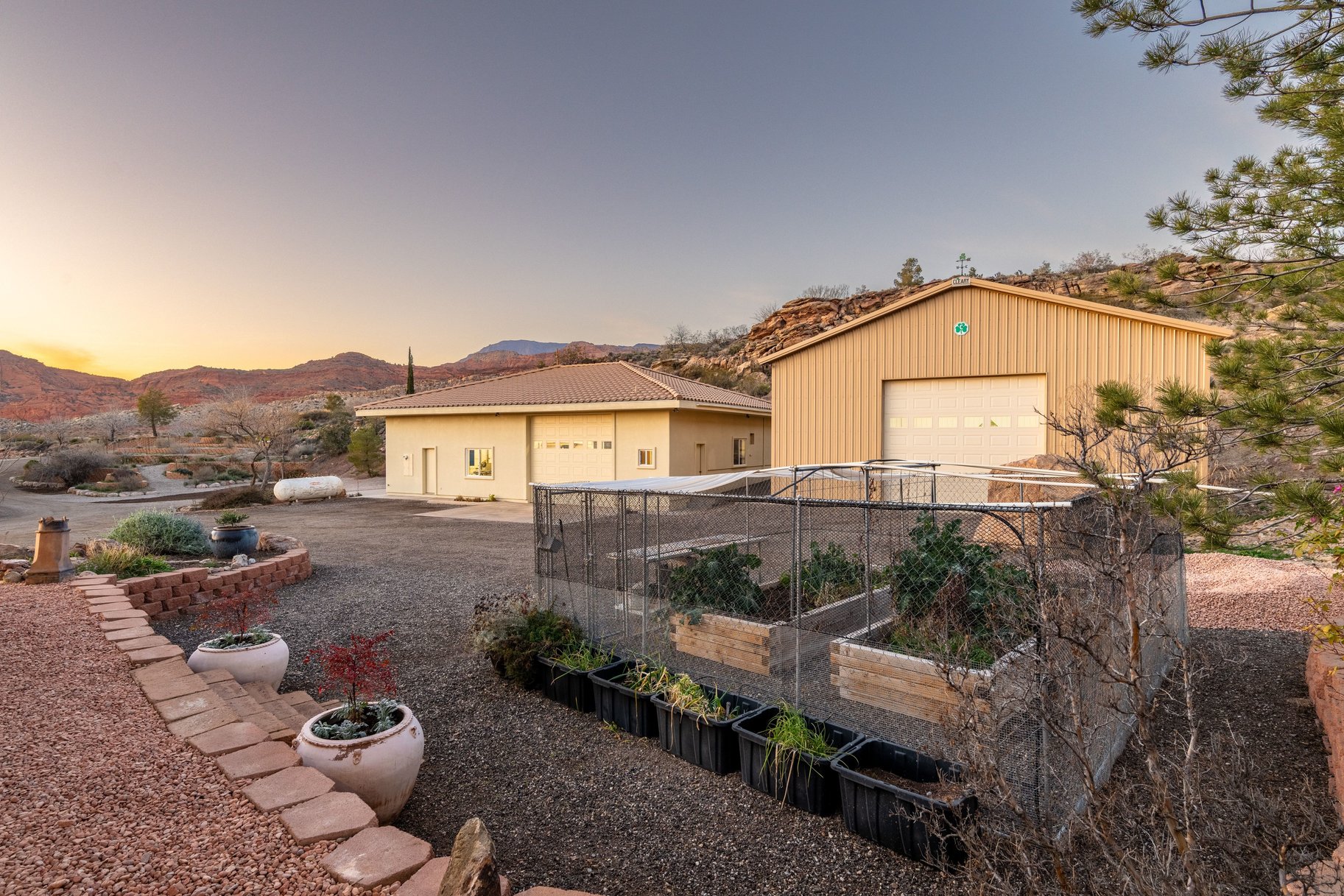View of front facade featuring a vegetable garden, a mountain view, a garage, and an outbuilding