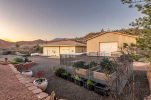 View of front facade featuring a vegetable garden, a mountain view, a garage, and an outbuilding