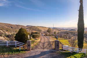 View of street featuring a mountain view, a view of rural / pastoral area, and a gate