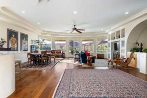 Living area with dark wood finished floors, a ceiling fan, a tray ceiling, and recessed lighting