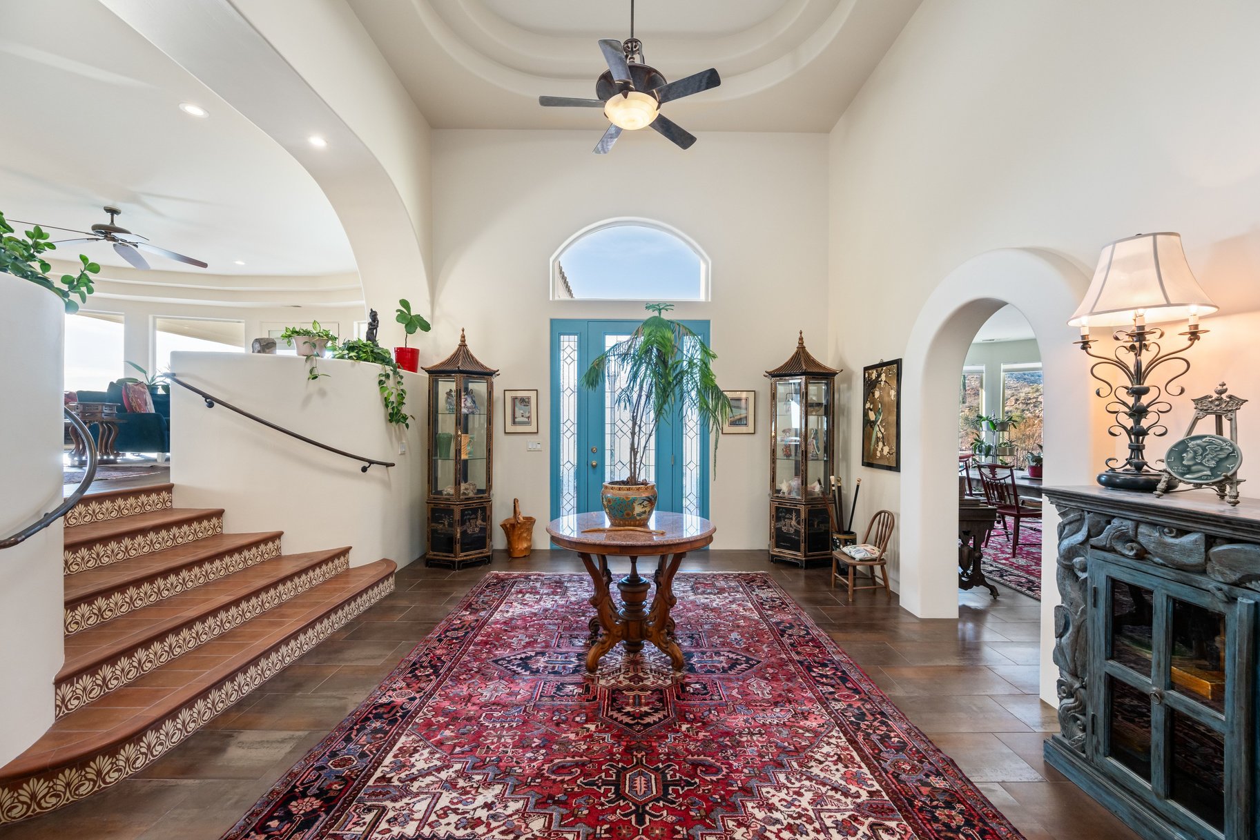 Foyer with ceiling fan, arched walkways, a raised ceiling, dark wood-style flooring, and recessed lighting