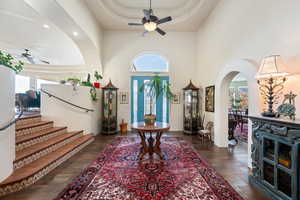 Foyer with ceiling fan, arched walkways, a raised ceiling, dark wood-style flooring, and recessed lighting