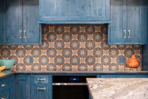 Kitchen with blue cabinetry and dark stone counters