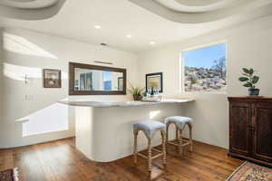 Bar area featuring hardwood / wood-style floors, healthy amount of natural light, recessed lighting, and light stone counters